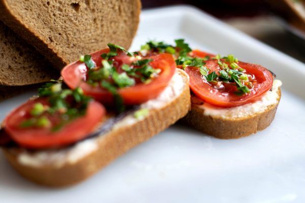 delicious-sandwiches-brown-toasts-with-fresh-vegetables-such-as-red-sliced-tomatoes-black-fried-eggplants-with-greens-top-white-plate